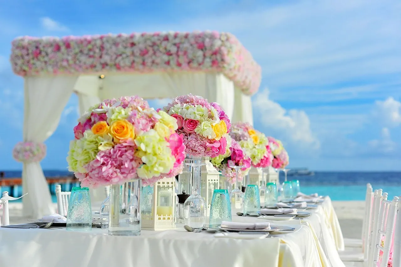 A reception table with flowers and glassware.