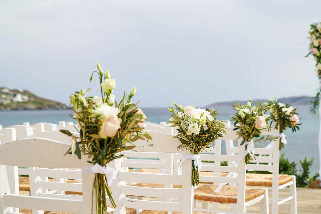 Chairs and flowers set for an outdoor ceremony.